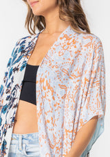 [Color: Lt Blue/Sand] A model wearing a stunning mid length kimono in a light blue mixed floral print. Featuring half length kimono sleeves, side slits, and an open front.