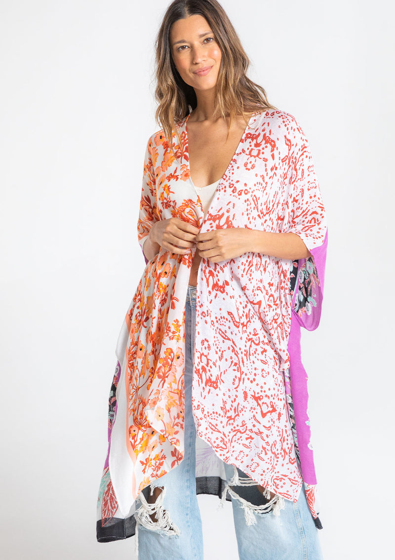 [Color: Seafoam/Lilac] A model wearing a stunning mid length kimono in a purple mixed floral print. Featuring half length kimono sleeves, side slits, and an open front.