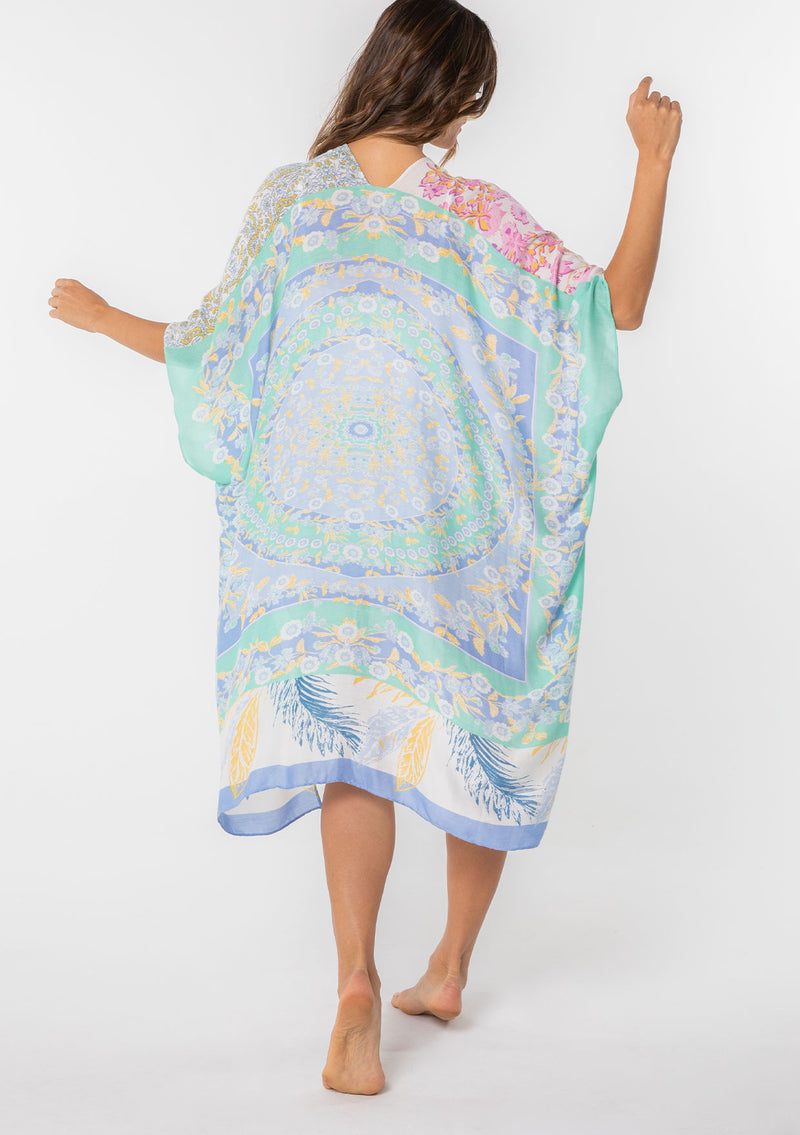 [Color: Sky/Seafoam] A model wearing a stunning mid length kimono in a blue mixed floral print. Featuring half length kimono sleeves, side slits, and an open front.