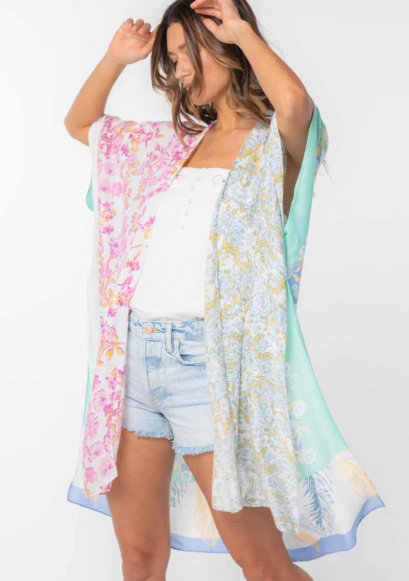 [Color: Sky/Seafoam] A model wearing a stunning mid length kimono in a blue mixed floral print. Featuring half length kimono sleeves, side slits, and an open front.