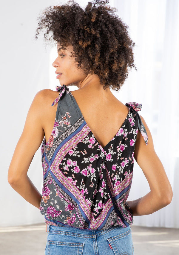 [Color: Black/Orchid] A model wearing a lightweight tie shoulder tank top in a patchwork floral print. With a surplice neckline in front and back and a smocked elastic hemline. 