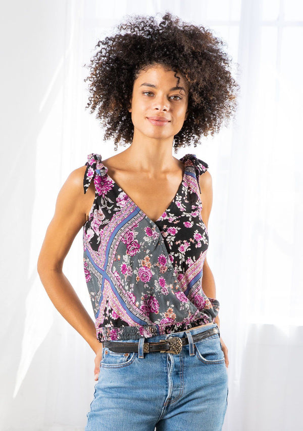 [Color: Black/Orchid] A model wearing a lightweight tie shoulder tank top in a patchwork floral print. With a surplice neckline in front and back and a smocked elastic hemline. 