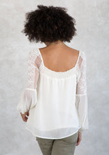 [Color: Ivory] A model wearing a romantic square neck blouse in an ivory dot chiffon. With a long voluminous lantern sleeve with embroidered dot mesh detail and a billowy relaxed fit. 