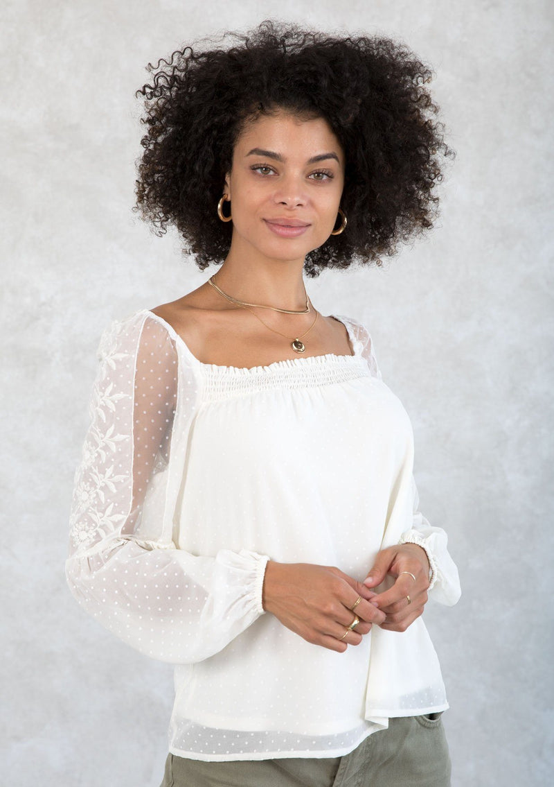 [Color: Ivory] A model wearing a romantic square neck blouse in an ivory dot chiffon. With a long voluminous lantern sleeve with embroidered dot mesh detail and a billowy relaxed fit. 