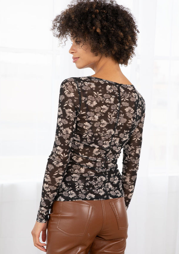 [Color: Black/Natural] A model wearing a black sheer mesh long sleeve tee in a natural floral print. With a round neckline and a slim fit.