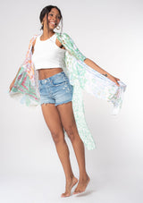 [Color: Mint/Sky] A model wearing a sheer lightweight mid length kimono in a mint green and sky blue mixed floral print. With half length kimono sleeves, side slits, and an open front.