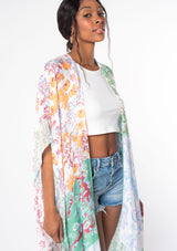 [Color: Mint/Sky] A model wearing a sheer lightweight mid length kimono in a mint green and sky blue mixed floral print. With half length kimono sleeves, side slits, and an open front.