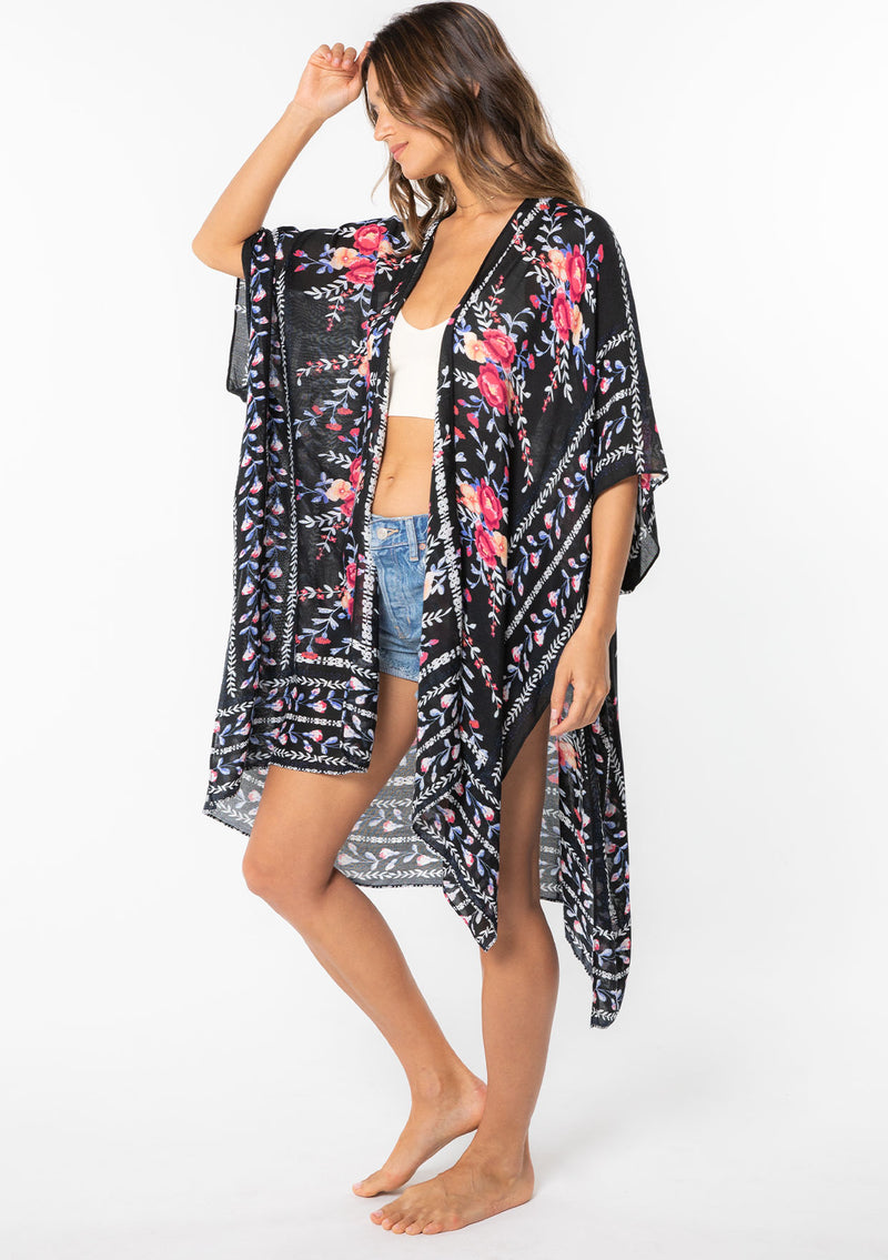 [Color: Royal Blue/Black] A model wearing a blue, black and pink floral border print kimono. 