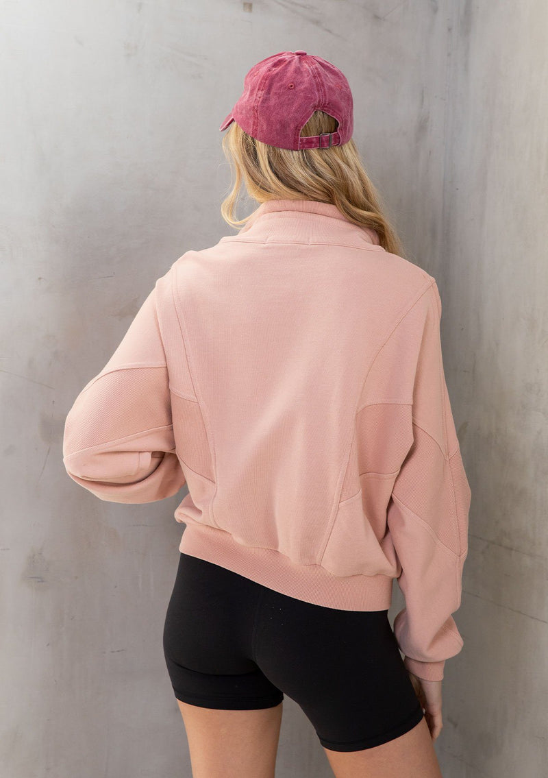 [Color: Pink] A model wearing a lounge worthy, vintage inspired funnel neck zip up sweatshirt. With a drawstring funnel neck, side pockets, and paneled details. 