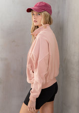 [Color: Pink] A model wearing a lounge worthy, vintage inspired funnel neck zip up sweatshirt. With a drawstring funnel neck, side pockets, and paneled details. 