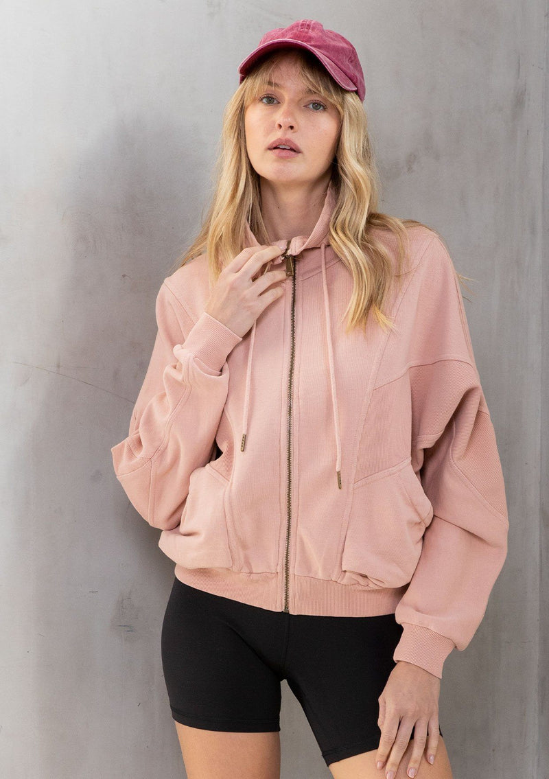 [Color: Pink] A model wearing a lounge worthy, vintage inspired funnel neck zip up sweatshirt. With a drawstring funnel neck, side pockets, and paneled details. 