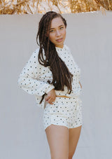 [Color: Ivory/Black] A woman standing outside wearing polka dot pull on jogging shorts. Featuring a drawstring waistband and side pockets. 