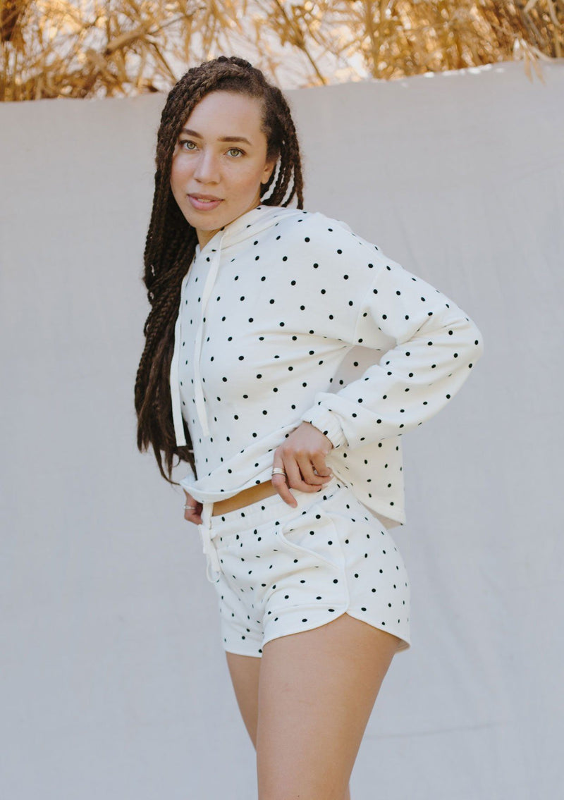 [Color: Ivory/Black] A woman standing outside wearing polka dot pull on jogging shorts. Featuring a drawstring waistband and side pockets. 