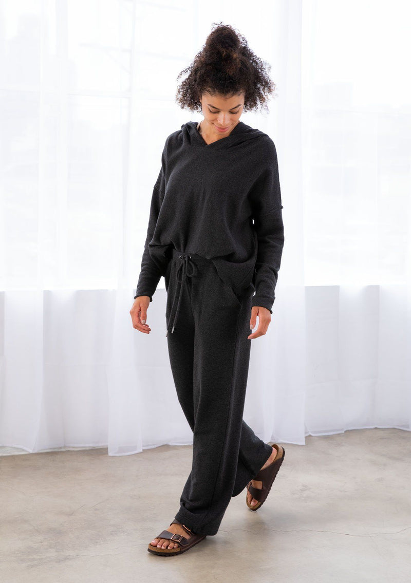 [Color: Black] A model wearing a black pull on style wide leg jogger pant made with soft French terry. With a drawstring waist and essential side pockets.