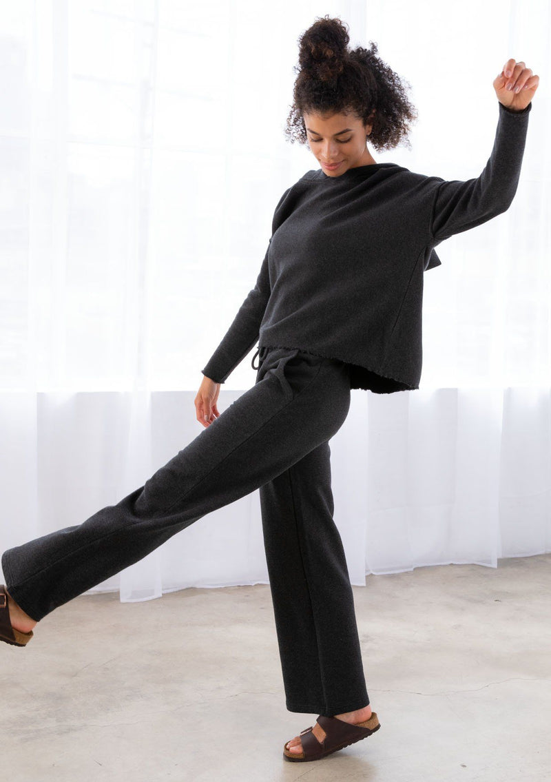 [Color: Black] A model wearing a black pull on style wide leg jogger pant made with soft French terry. With a drawstring waist and essential side pockets.