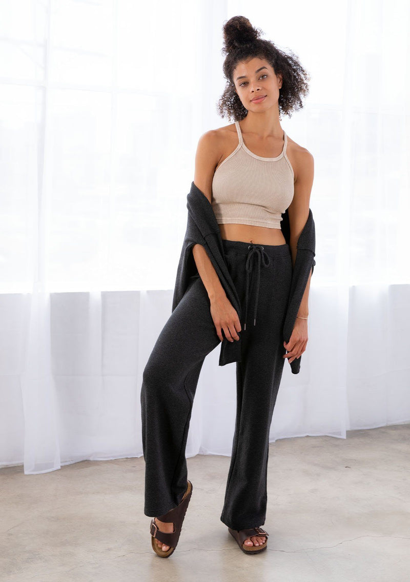 [Color: Black] A model wearing a black pull on style wide leg jogger pant made with soft French terry. With a drawstring waist and essential side pockets.