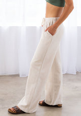 [Color: Seashell] A model wearing a seashell beige pull on style wide leg jogger pant made with soft French terry. With a drawstring waist and essential side pockets.