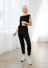 [Color: Black] A model wearing a soft and stretchy legging pant. With a cropped leg, side gathered details at the ankle, and an elastic waist.