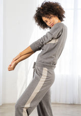 [Color: Heather Smoke/Stone] A model wearing a soft grey jogger pant with a contrast stripe along the side of the leg. Featuring a drawstring waist, a long tapered leg, and ribbed cuff. 