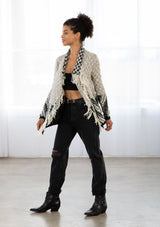 [Color: Light Heather Grey/Black] A model wearing a chunky marled knit bohemian cardigan in a grey and black pattern. With a fringed hemline, long sleeves, and contrast trim.