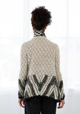 [Color: Light Heather Grey/Black] A model wearing a chunky marled knit bohemian cardigan in a grey and black pattern. With a fringed hemline, long sleeves, and contrast trim.