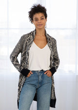 [Color: Navy/Nude] A woman wearing a navy and nude bohemian diamond pattern mid length cardigan. With a shawl collar, an open front, and contrast ribbed trim. 