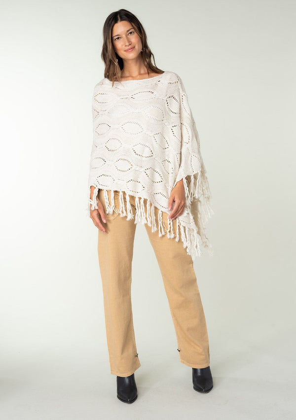 [Color: Heather Cream] A vintage inspired sweater poncho knit from a cream speckled yarn. With a fringed hemline. 