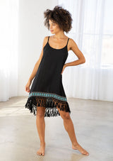 [Color: Black] A model wearing a black sleeveless mini dress with a scooped neckline, low scooped back, and fringed hemline.