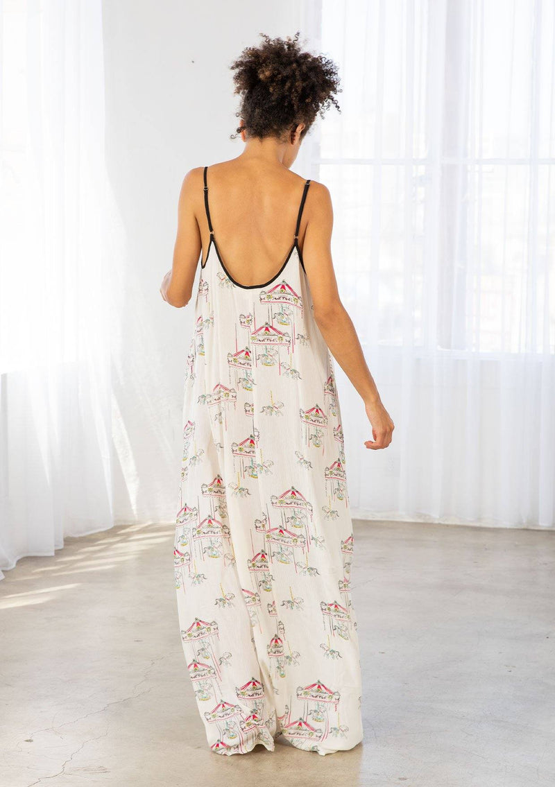 [Color: Cherry/Natural] A model wearing a billowy maxi dress with a carousel print throughout. Featuring a front keyhole detail with tie, side pockets, and spaghetti straps. 