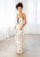 [Color: Cherry/Natural] A model wearing a billowy maxi dress with a carousel print throughout. Featuring a front keyhole detail with tie, side pockets, and spaghetti straps. 