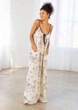 [Color: Cherry/Natural] A model wearing a billowy maxi dress with a carousel print throughout. Featuring a front keyhole detail with tie, side pockets, and spaghetti straps. 