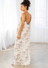 [Color: Cherry/Natural] A model wearing a billowy maxi dress with a carousel print throughout. Featuring a front keyhole detail with tie, side pockets, and spaghetti straps. 