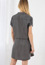 [Color: Ash Wash] A blond model wearing a casual short sleeve shirt dress. Featuring an adjustable drawstring waist for definition, side pockets, and a chic shirttail hemline.