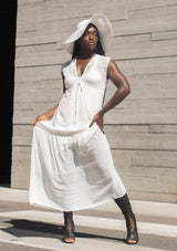 [Color: Off White] A woman wearing a sheer off white chiffon swiss dot maxi dress. With a drawstring empire waist, tiered skirt, v neckline, and lining.