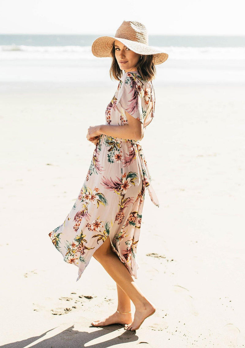 [Color: Silver] A woman on the beach wearing a tropical floral print mid length dress. With short kimono sleeves, a v neckline, an adjustable waist tie, and an open back.