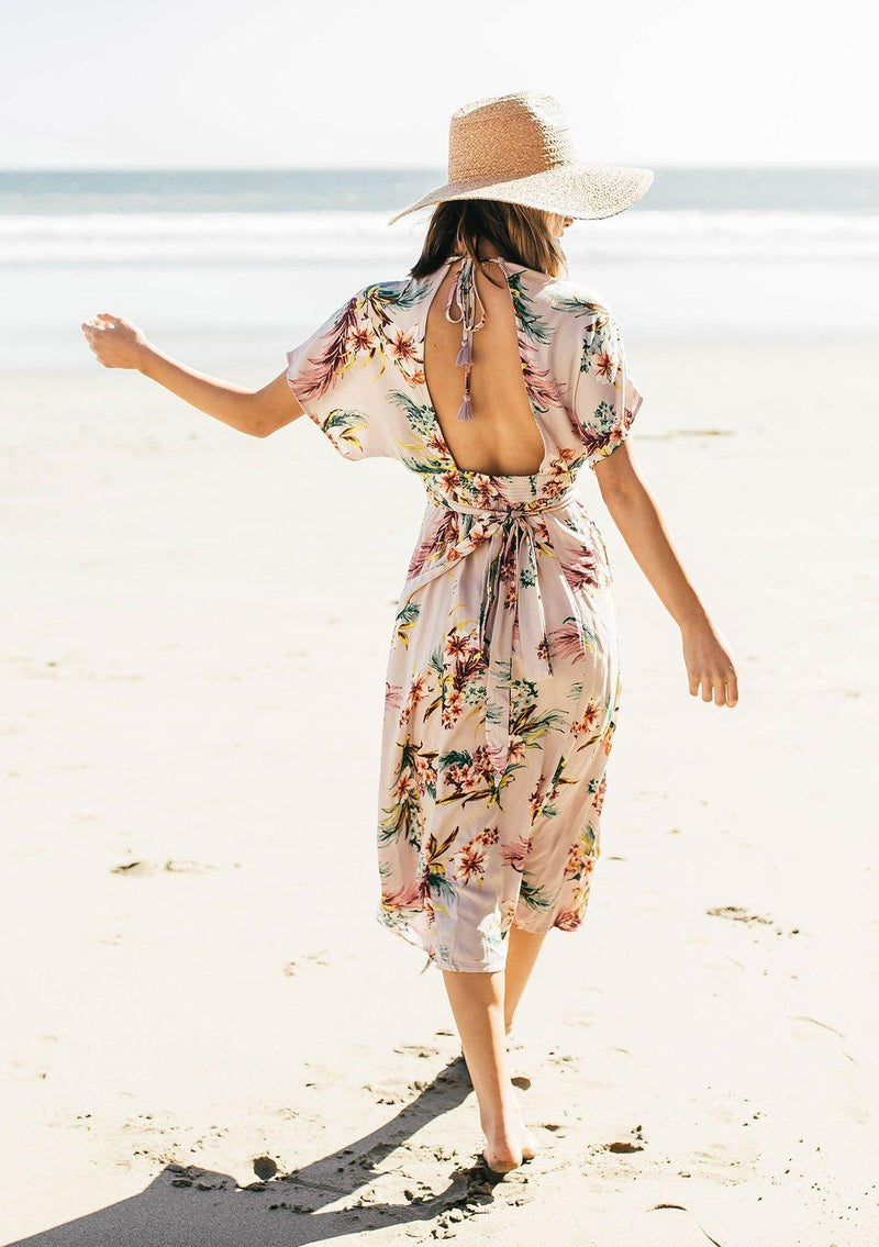 [Color: Silver] A woman on the beach wearing a tropical floral print mid length dress. With short kimono sleeves, a v neckline, an adjustable waist tie, and an open back.