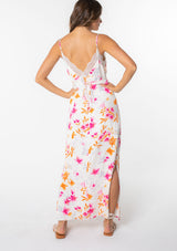 [Color: Ivory/Fuchsia] A model wearing a white maxi slip dress with pink floral print and lace trim. 