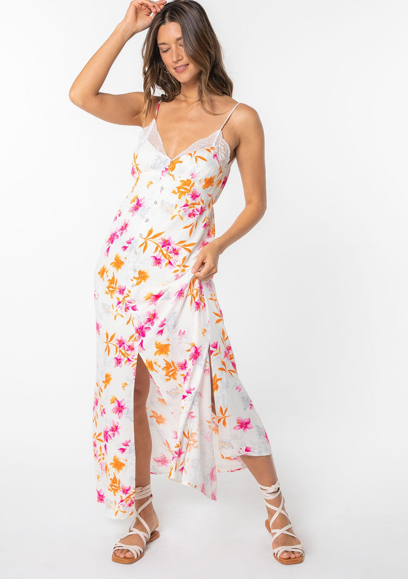 [Color: Ivory/Fuchsia] A model wearing a white maxi slip dress with pink floral print and lace trim. 