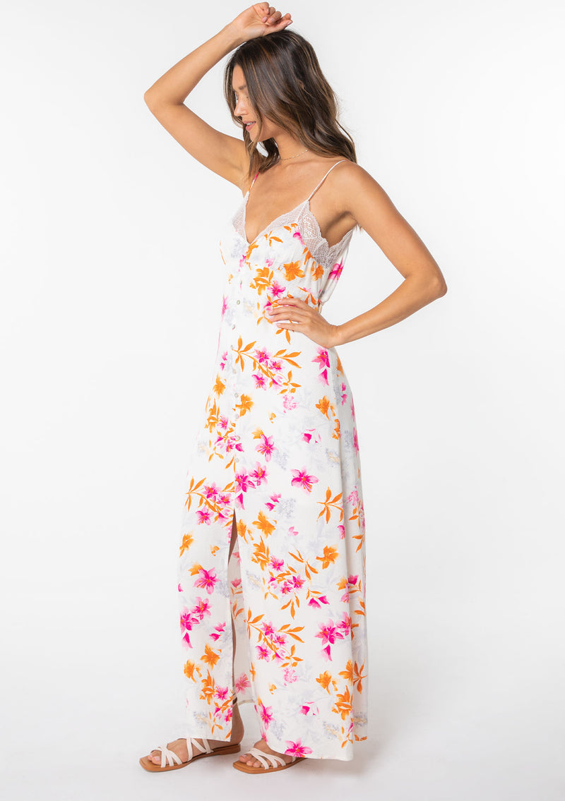 [Color: Ivory/Fuchsia] A model wearing a white maxi slip dress with pink floral print and lace trim. 