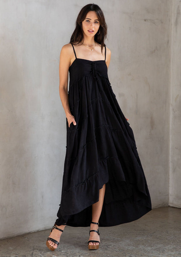 [Color: Black] A model wearing an ultra flowy sleeveless maxi dress, featuring a sweetheart neckline, an empire waist, and ruffled details. Perfect beach dress. 