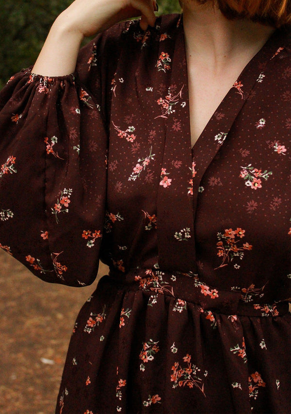 [Color: Merlot Rose] A romantic, vintage inspired floral mini dress. Featuring a v neckline, a waist defining tie back detail, and voluminous long sleeves.