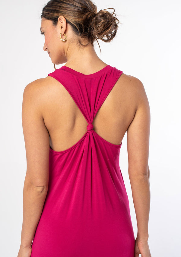 [Color: Mulberry] A model wearing a soft and stretchy sleeveless pink maxi dress. With a round crew neckline, a sexy side slit, a racer back with a knot detail, and a relaxed fit.