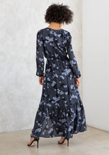 [Color: Slate/Grey] A model wearing a slate blue and grey blossom floral print maxi dress. With a mini pom trimmed v neckline, an elastic waist, a side slit, voluminous long sleeves with an elastic wrist cuff, and attached lining. 