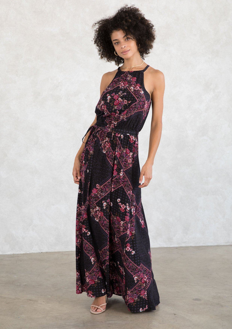 [Color: Plum/Berry] A model wearing a sexy bohemian halter maxi dress in an autumnal pink and purple floral print. With an elastic waist, an open tie back detail, a drawstring neckline, and aa tiered paneled skirt for movement and shape. 