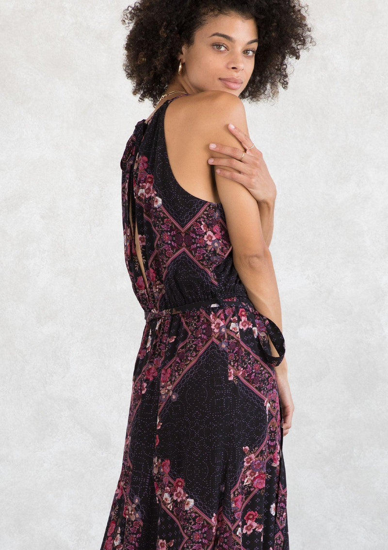 [Color: Plum/Berry] A model wearing a sexy bohemian halter maxi dress in an autumnal pink and purple floral print. With an elastic waist, an open tie back detail, a drawstring neckline, and aa tiered paneled skirt for movement and shape. 