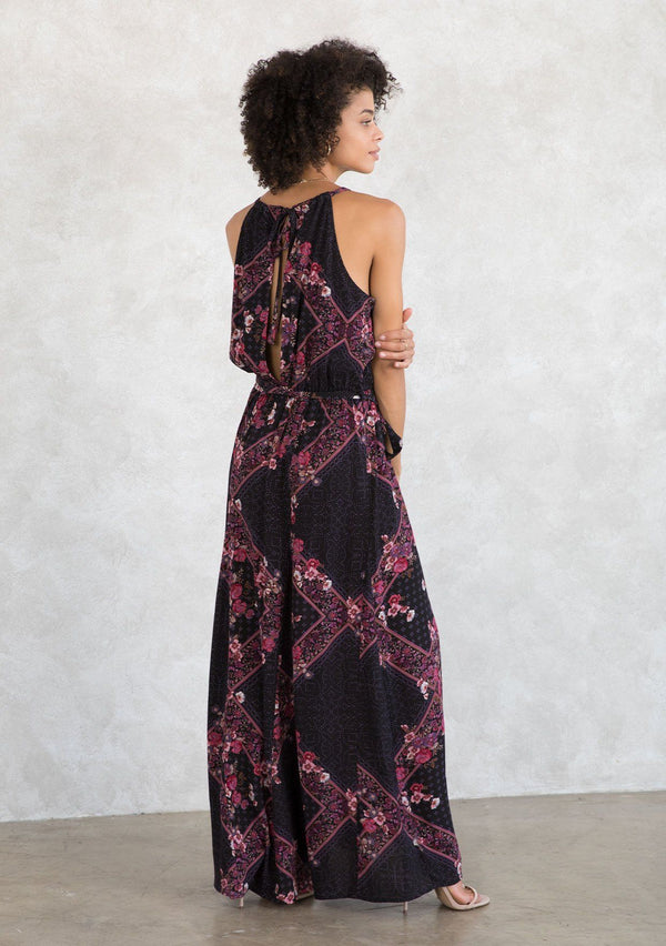 [Color: Plum/Berry] A model wearing a sexy bohemian halter maxi dress in an autumnal pink and purple floral print. With an elastic waist, an open tie back detail, a drawstring neckline, and aa tiered paneled skirt for movement and shape. 