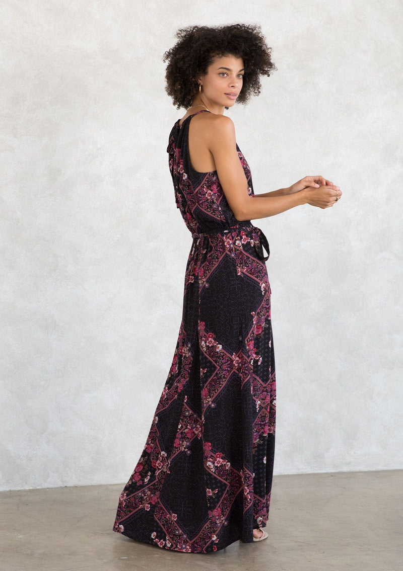 [Color: Plum/Berry] A model wearing a sexy bohemian halter maxi dress in an autumnal pink and purple floral print. With an elastic waist, an open tie back detail, a drawstring neckline, and aa tiered paneled skirt for movement and shape. 