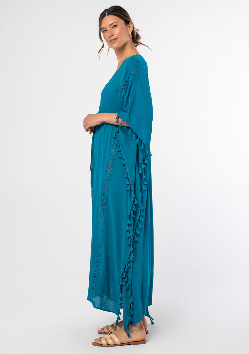 [Color: Teal] A woman wearing a sheer teal bohemian beach cover up maxi dress with lace and tassel trim and side slits. A kimono kaftan maxi dress perfect for vacations! 