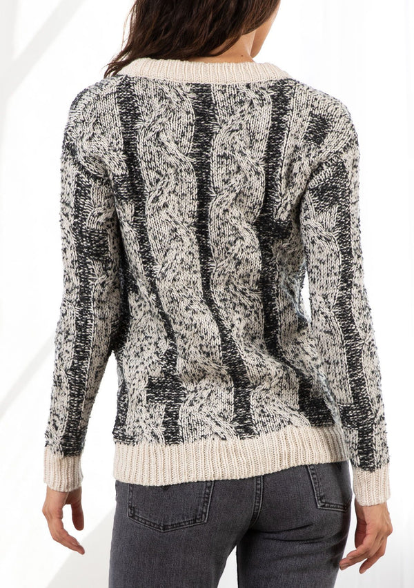 [Color: Black/Cream] A model wearing a cozy black and cream speckled cardigan. With a large button front and a v neckline. 