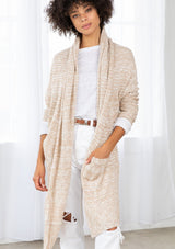 [Color: Nude/Ivory] A model wearing a beige knit reversible cardigan. With long sleeves, a waterfall open front, side pockets, and a shawl collar. 